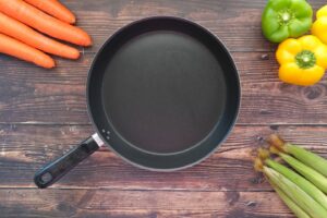 empty frying pan and vegetables on table .